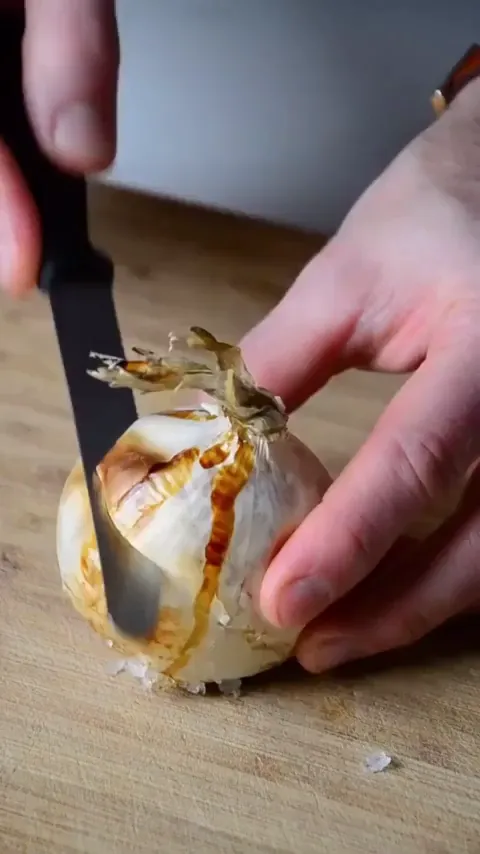 Delicious_Delilah frame at 00:07, Delilah’s hands—part chef, part chaos conductor—hack at charred onion layers like they’re dissecting Twitter trolls