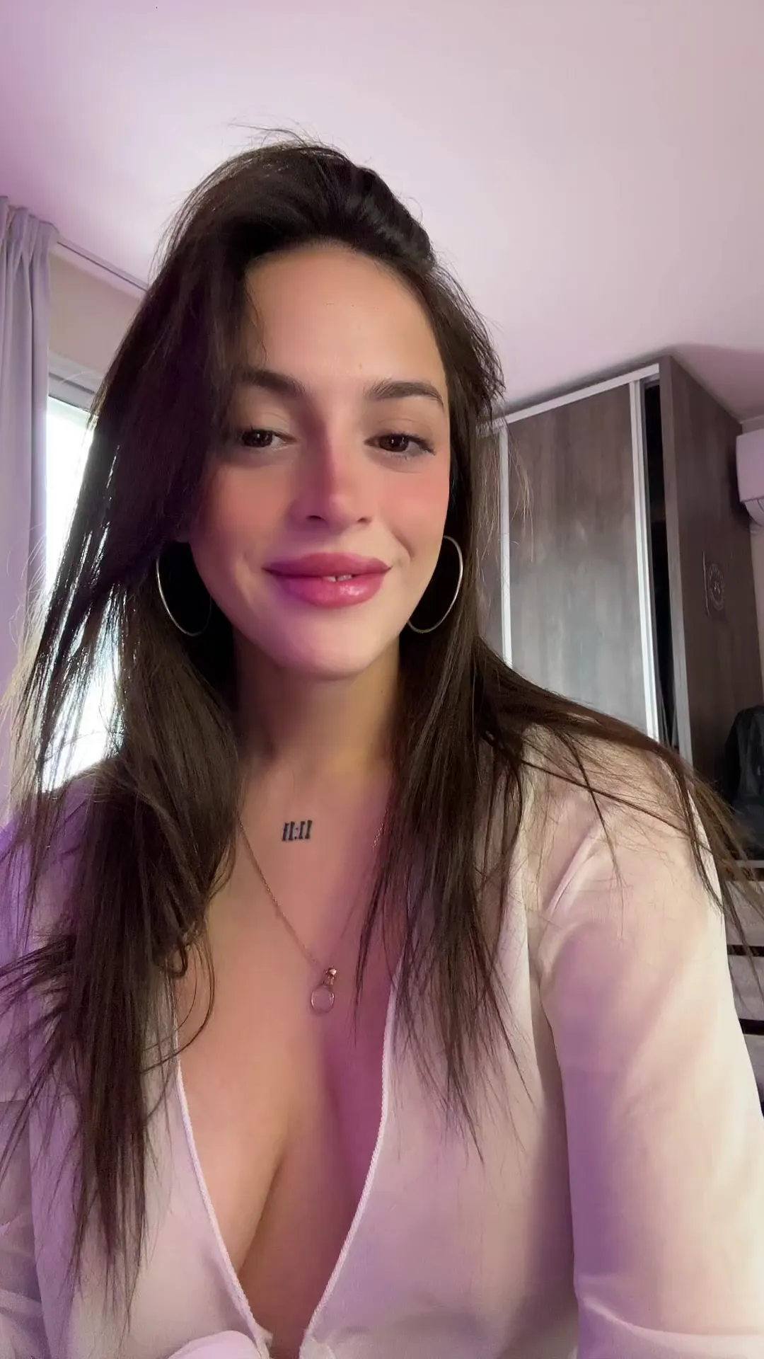 Hot_Bad_626 frame at 00:00, Innocence meets ink: Her '008' collarbone tattoo peeks through a crisp white V-neck, tousled hair framing a demure smile
