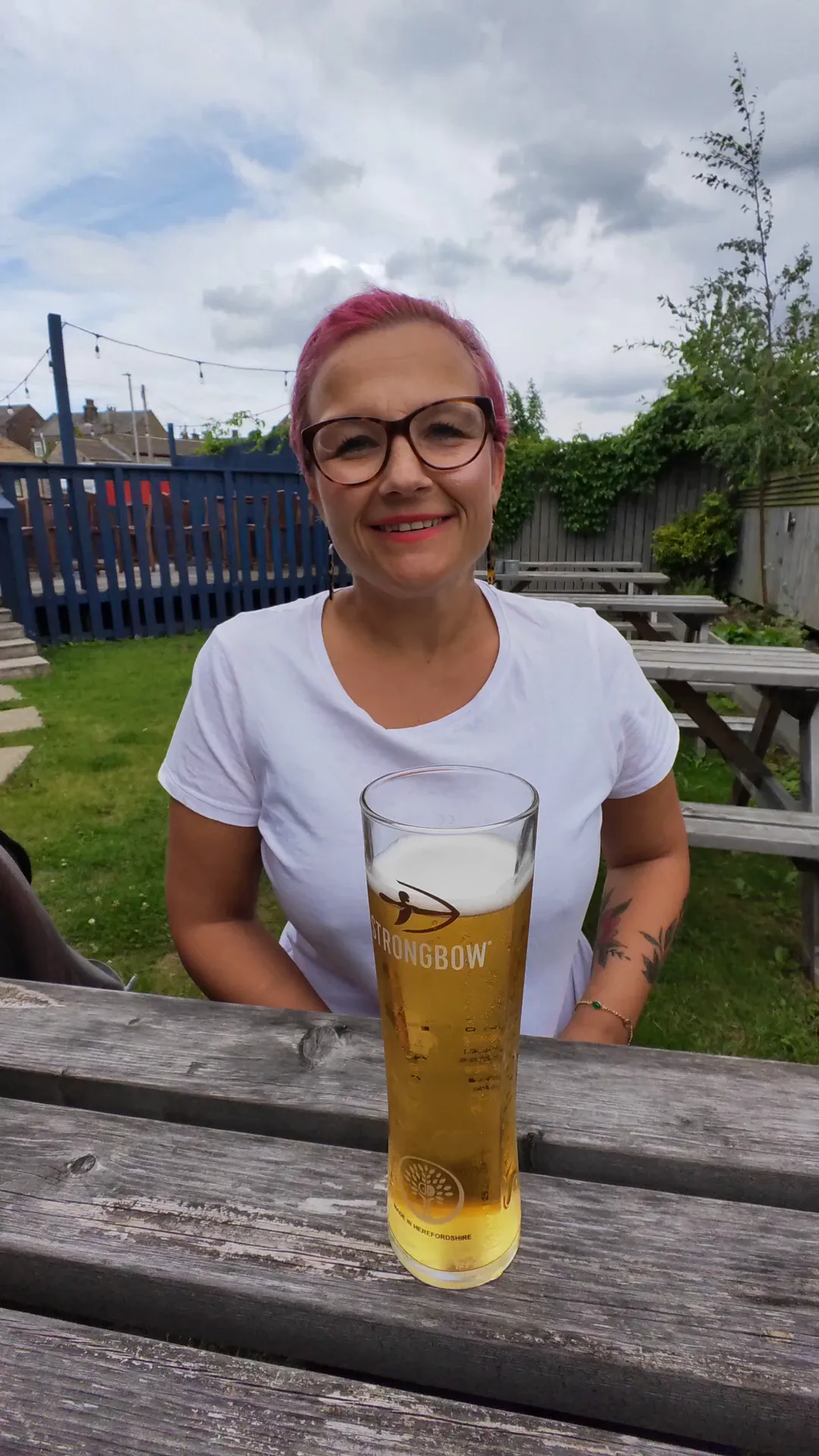 Ok_Sample9234 frame at 00:00, A cheeky daytime tease! Ok_Sample9234’s pink hair and glasses add playful contrast to her earthy vibe, while the picnic table and beer nod to her casual confidence