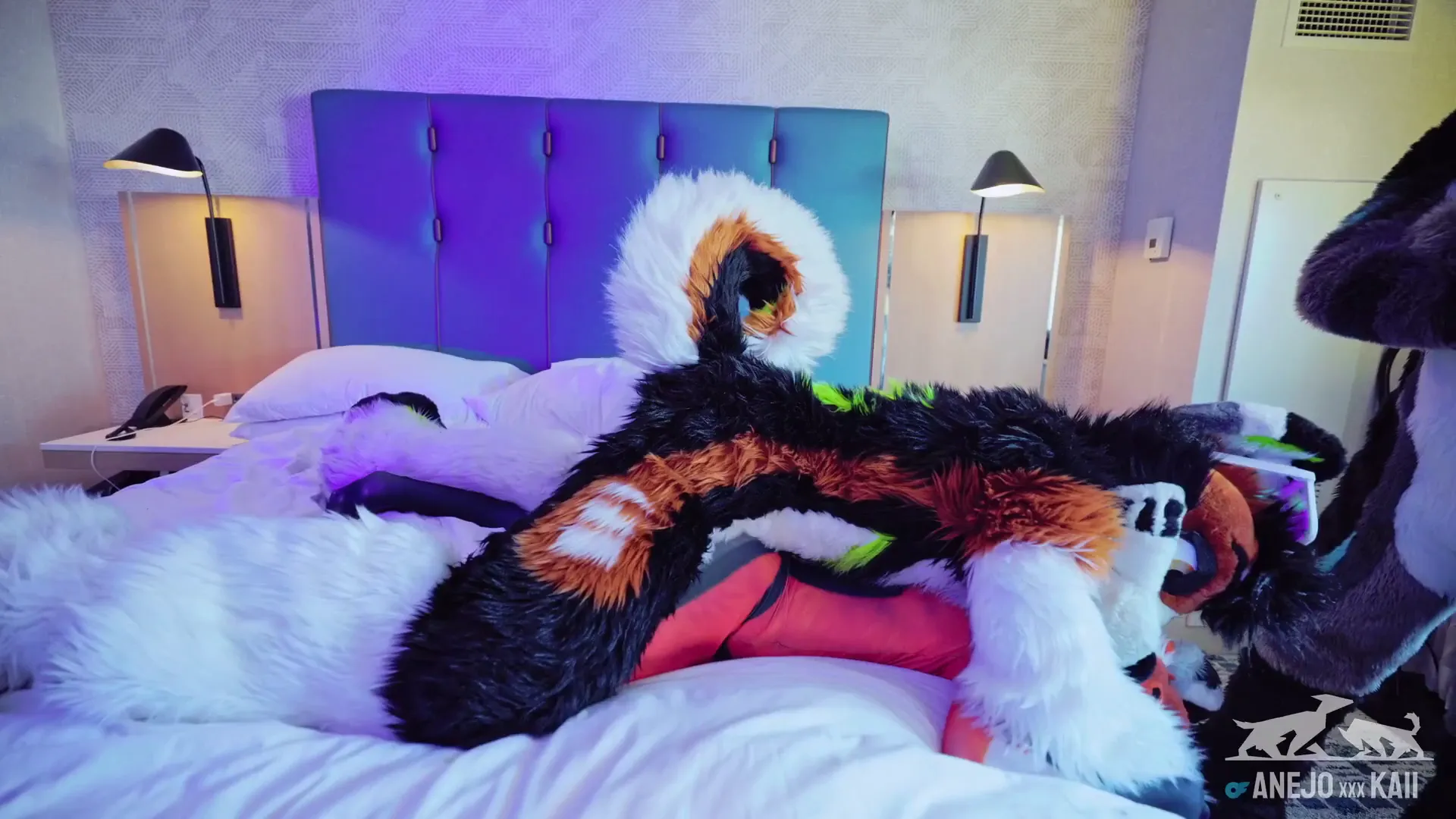 SassyOnMane frame at 00:50, SassyOnMane’s primal alter ego lounges like a fox in a den of suburban decadence—fluffy tail draped over crisp white sheets, orange-and-black fur clashing with the sterile blue headboard