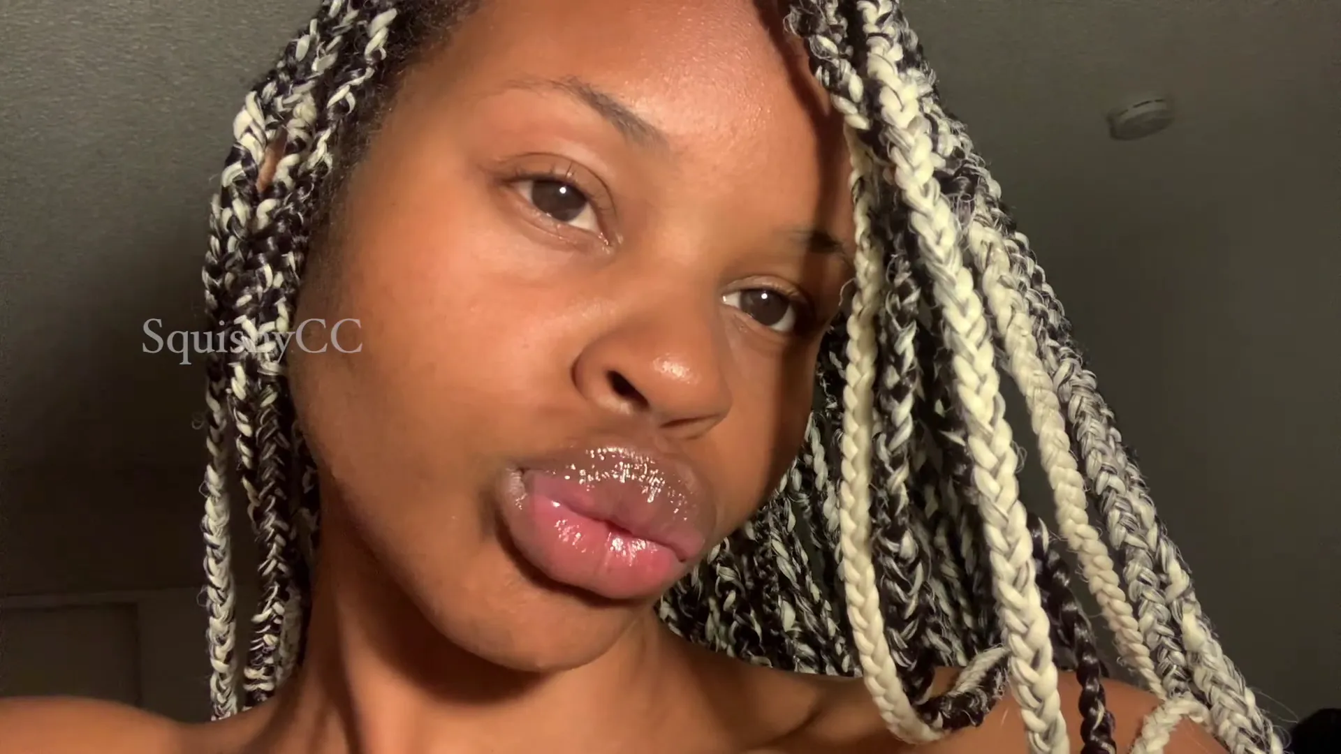 ccsquishy frame at 00:02, Maroon strapless top clings to her gravity-defying curves, while two-toned braids frame a shy smirk